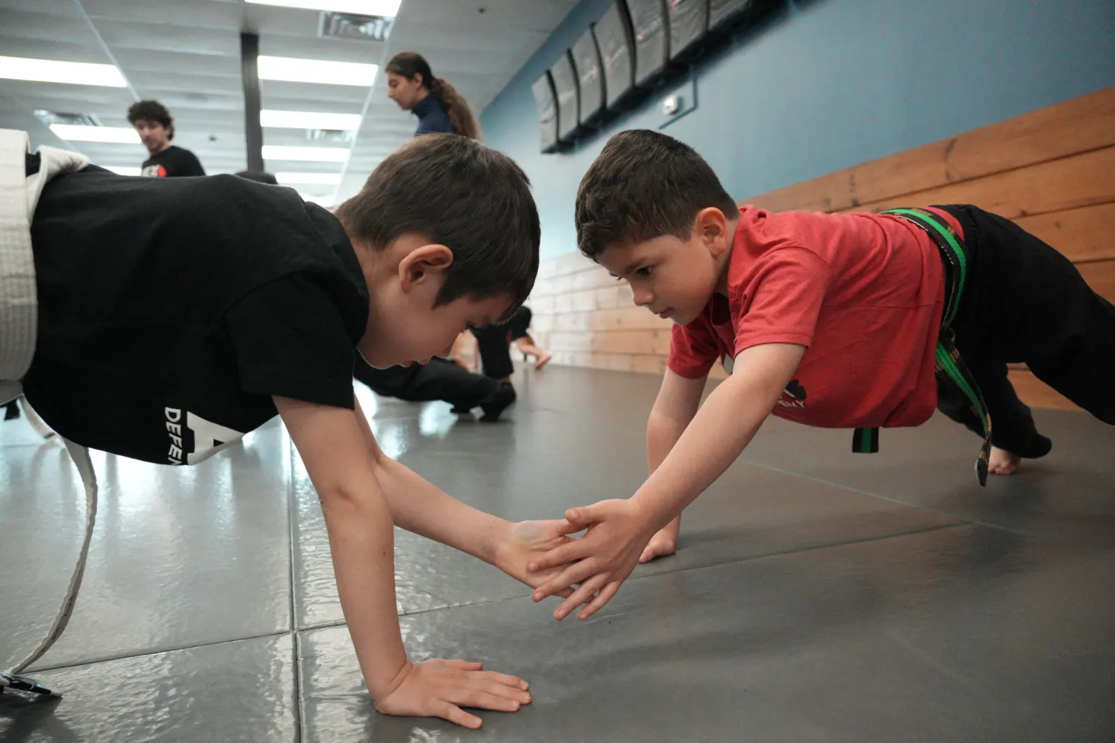 Kids in Apex shirts doing a partner push-up drill