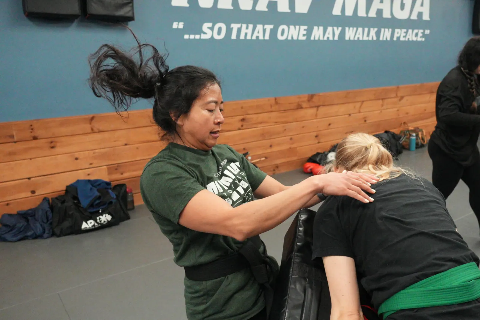 Adult Krav Maga students practicing a knee strike on a held pad
