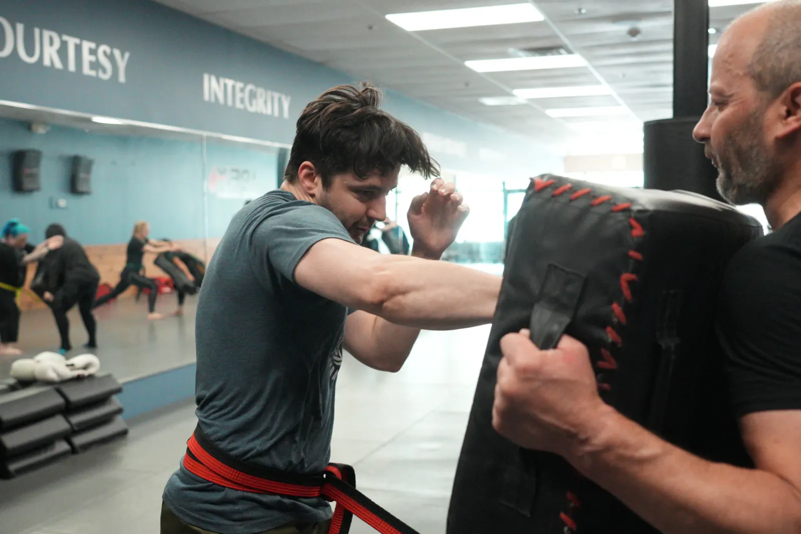 Adult student punching into a held shield